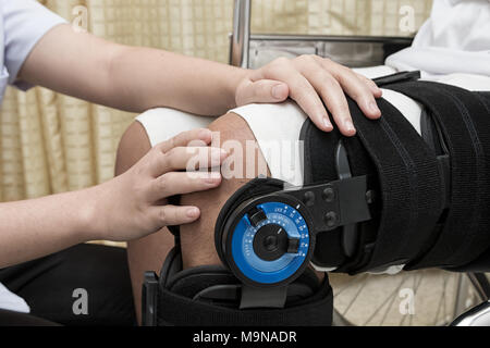 Weibliche Physiotherapie einstellen zu Fuß am Bein des Patienten im Rollstuhl Strebe Stockfoto