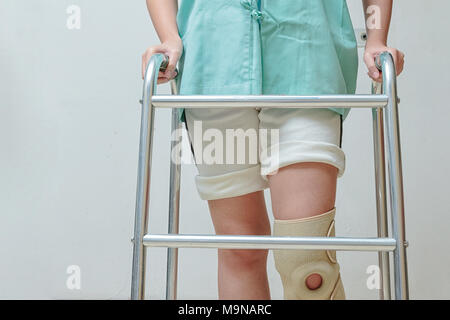 Frau gehen auf Zuckerrohr, das Tragen von Knie Unterstützung im rehab Zentrum Stockfoto