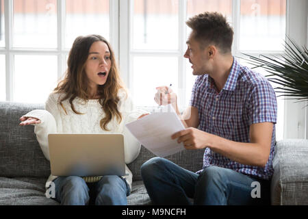 Besorgt Unglückliche Paare streiten über Schuld oder hohen inländischen Rechnungen mit Laptop und Dokumente, junge Familie mit Streit über Geld zu vergeuden bankr Stockfoto