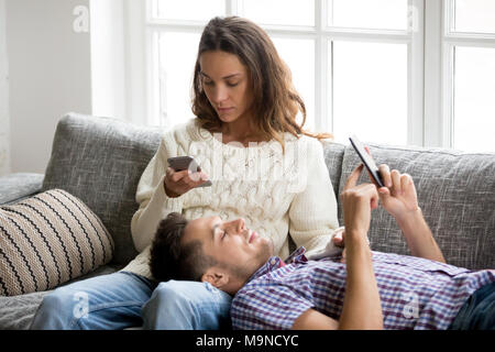 Mobile sucht Konzept, junges Paar gegenseitig ignorieren mit Smartphones entspannt auf einem Sofa, tausendjährigen Mann und Frau besessen mit neuen Anwendungen oder Soci Stockfoto