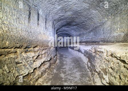 Die alte Sandstein Tunnel, Höhlen abgebaut. Die Höhle. Sandstein Tunnel feuchten Wänden. Trockene Kanal in den felsigen Untergrund geschnitzt Stockfoto