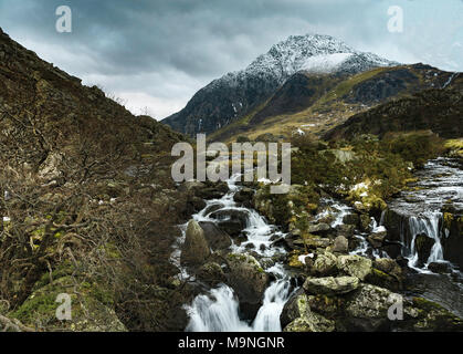 Einen schneebedeckten Berg mit Tryfan Afon Ogwen cascading seinen Weg den Berg hinunter in die Nant Ffrancon Tal. Stockfoto