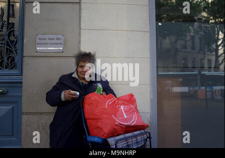 Obdachlose Frau sitzt auf der Straße mit großen roten Beutel - Boulevard Barbès, Paris, Frankreich Stockfoto