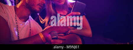 Musiker mit Handy beim Üben im Nachtclub Stockfoto