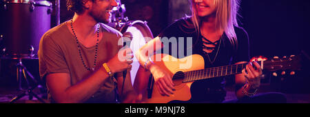 Männliche und weibliche Darsteller sitzen auf der Bühne im beleuchteten Nachtclub Stockfoto