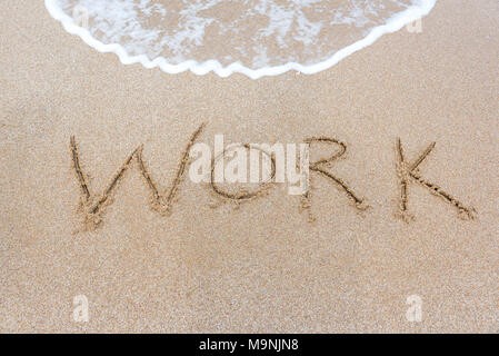 Das Wort Inschrift arbeiten auf dem Sand am Strand. Stockfoto