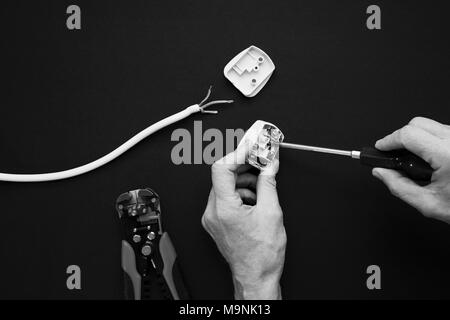 Elektrische Stecker eröffnet und ist offener Schraube einschrauben. Schwarzweiß gedreht Stockfoto