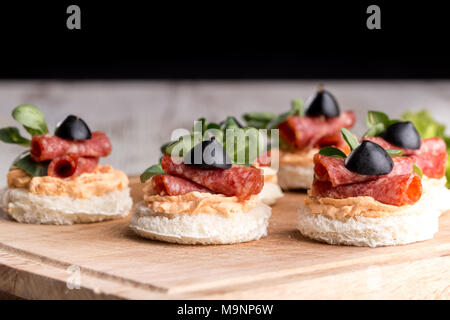 Leckere Häppchen mit Salami und Gewürze auf einem hölzernen Hintergrund Stockfoto