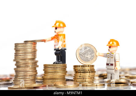 Zwei Arbeiter Puppen sammeln und Stack Euro-Münzen auf weißem Hintergrund. Stockfoto