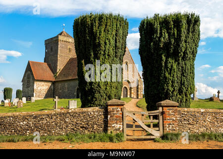 Eingang zur Kirche von St. Martha's Hill, flankiert von zwei Bäumen, mit einem blauen Himmel an einem sonnigen Tag in den North Downs mit Grabsteinen, Wand- und Gate Stockfoto