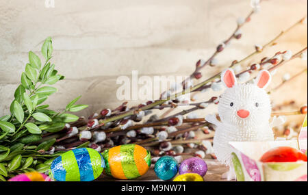 Ostern Dekoration, Spielzeug Gummi Bunny, Schokolade Eier und Strauch auf rustikalen Hintergrund Stockfoto