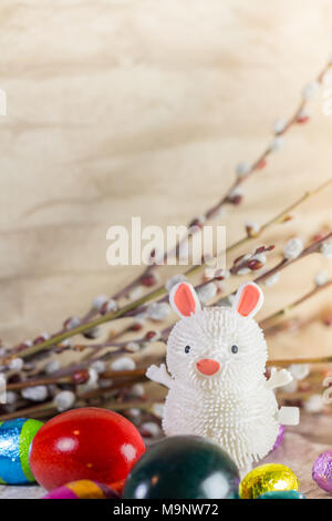 Ostern Dekoration, Spielzeug Gummi Bunny, Schokolade Eier und Strauch auf rustikalen Hintergrund Stockfoto