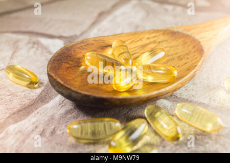 Lebertran Kapseln omega-3 auf Holzlöffel, rustikalem Stein Hintergrund Stockfoto