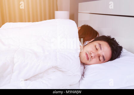 Kranken jungen Mann schlafend auf dem Bett mit seiner Frau Stockfoto