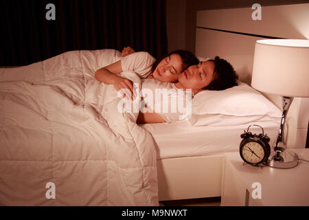 Glückliches junges attraktives Paar umarmen und schlafend auf dem Bett in der Nacht Stockfoto