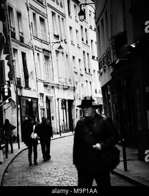 Typischen schmalen gepflasterten Straße in Paris mit einem Mann in den Vordergrund. Stockfoto