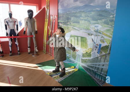 Ein Junge imaginären spielt er fliegen ist während einer Schanze bei den Olympischen Skispringen Turm von alpensia Resort in Südkorea. Die alpensia Resort ist ein Skigebiet und eine touristische Attraktion. Es ist auf dem Gebiet der Gemeinde von daegwallyeong-myeon befindet sich in der Grafschaft von Pyeongchang, die Olympischen Winterspiele hosting im Februar 2018. Das Skigebiet ist ca. 2,5 Stunden von Seoul oder Incheon Airport mit dem Auto, überwiegend alle Autobahn. Alpensia hat sechs Pisten für Ski und Snowboard, mit bis zu 1,4 km (0.87 mi) lang, für Anfänger und Fortgeschrittene, und einen Bereich für reserviert Stockfoto