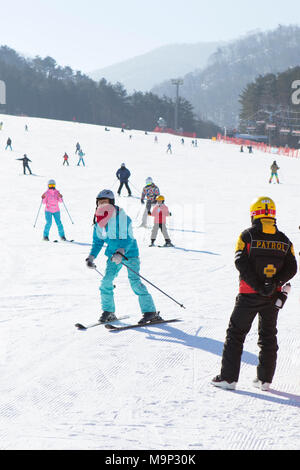 Ein Ski patroller beobachtet die bunny Neigung an Yongpyong, Verhütung von Unfällen. Das Yongpyong-resort (Dragon Valley) Ski Resort ist ein Skigebiet in Südkorea, in Daegwallyeong-myeon, Pyeongchang, Gangwon-do. Es ist die größte Ski- und Snowboard Resorts in Korea. Das Yongpyong-resort bewirten die technischen Ski alpin Veranstaltungen für die olympischen Winterspiele und Paralympics 2018 in Pyeongchang. Einige Szenen der 2002 Korean Broadcasting System drama Winter Sonata wurden im Resort gedreht. Stockfoto