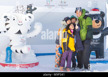 Eine Familie ist eine Gruppe selfie in Alpensia Resort, mit den beiden Maskottchen (Soohorang und Bandabi) der olympischen Winterspiele und Paralympics 2018. Die alpensia Resort ist ein Skigebiet und eine touristische Attraktion. Es ist auf dem Gebiet der Gemeinde von daegwallyeong-myeon befindet sich in der Grafschaft von Pyeongchang, die Olympischen Winterspiele hosting im Februar 2018. Das Skigebiet ist ca. 2,5 Stunden von Seoul oder Incheon Airport mit dem Auto, überwiegend alle Autobahn. Alpensia hat sechs Pisten für Ski und Snowboard, mit bis zu 1,4 km (0.87 mi) lang, für Anfänger und Fortgeschrittene, und ein Stockfoto