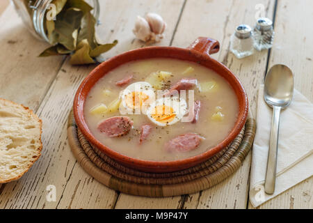 Traditionelle polnische Suppe namens Zurek mit Eiern und Würstchen von Gewürzen umgeben Stockfoto