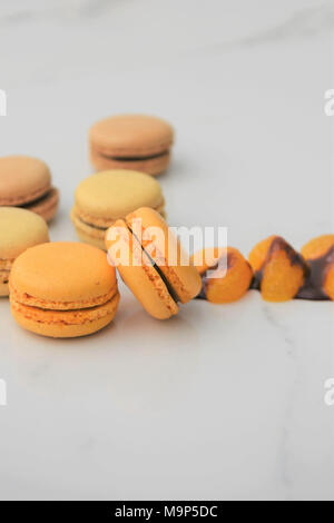 Schokolade und Orange geschmack Makronen Kekse auf weißem Marmor Stockfoto