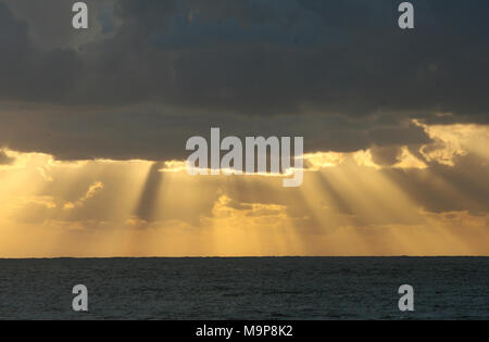 Sonnenstrahlen durch die Wolken im Meer Stockfoto