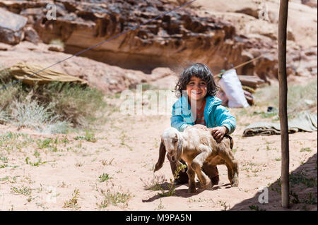 Junge beduinischen Mädchen spielen mit Baby Ziege im Wadi Rum Wüste nahe der Grenze zu Saudi-Arabien. Stockfoto