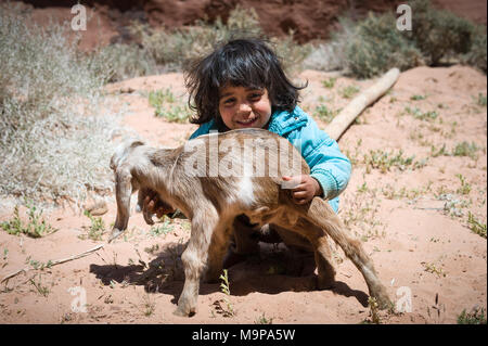 Junge beduinischen Mädchen spielen mit Baby Ziege im Wadi Rum Wüste nahe der Grenze zu Saudi-Arabien. Stockfoto