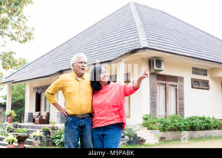 Gerne ältere Paare mit Daumen hoch vor ihrem neuen Haus Stockfoto