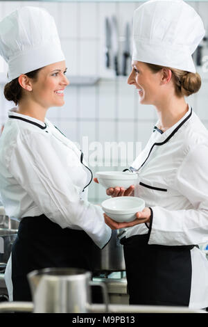 Weibliche Chefs in der gewerblichen Küche tragen weiße Uniformen Stockfoto