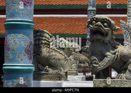 Detail der Bildhauerkunst im Grand Palace in Bangkok übersicht Wächterlöwen, dekoriert mit blauen Keramik Säule mit roten Dachziegeln im Hintergrund Stockfoto