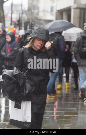 London, Großbritannien. Am 28. März 2018. Fußgänger Schutz vor dem kalten Regen im Aktionsbereich auf einem nassen kalten Tag Stockfoto