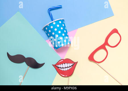 Flach Papier Becher mit Trinkhalm und Photo Booth Requisiten auf bunten Pastelltönen Hintergrund minimalen Begriff. Stockfoto