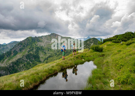 Wanderer sind in einem kleinen See, Schladminger Höhenweg, Schladminger Tauern, Schladming, Steiermark, Österreich wider. Stockfoto