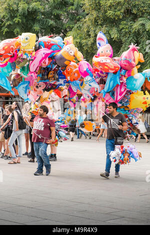 Zwei Straßenhändler nehmen eine große Auswahl an Luftballons in einem Plaza in Barcelona, Spanien Stockfoto