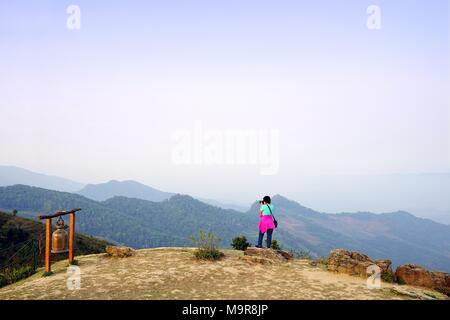 Frau mit Kamera und steht auf dem Berg mit Blick auf den Blick auf die wunderschönen Berge an Doi Pha Stockfoto