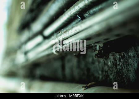 Sehr schmutzig elektrische Kabel entlang einer dunklen Betonwand Stockfoto