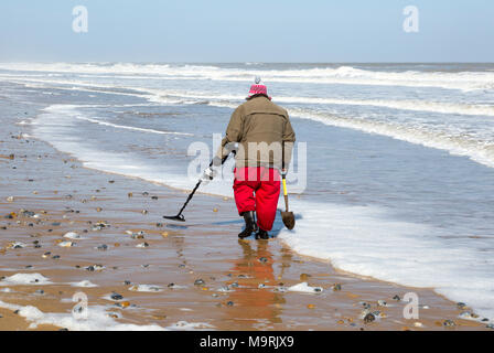 Männliche detectorist mit Metalldetektor entlang Sandstrand Hemsby, Norfolk, England, Großbritannien Stockfoto