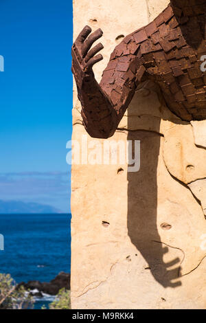 Abstrakte Detail der Skulptur zeigt rostiges Metall Arm und Schulter mit Schatten auf Stein Hintergrund und blauen Himmel und Meer an der Seite Stockfoto