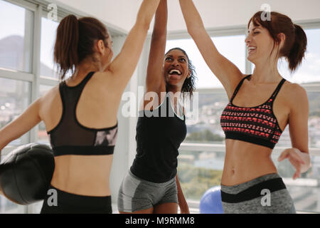 Freundliche Frauen mit Medizinball ihre Hände zusammen im Fitness Studio. Mädchen hoch fünf Nach erfolgreichem Training Session. Stockfoto