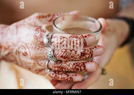 Weibliche Hände dekorativ durch Henna mit Tasse Masala Tee farbige Stockfoto