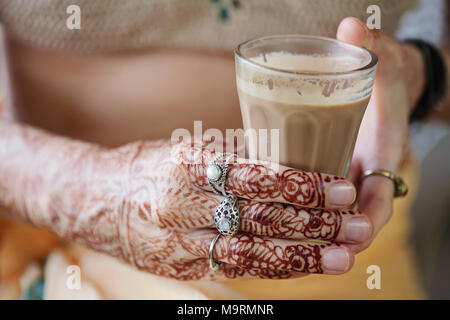 Weibliche Hände dekorativ durch Henna mit Tasse Masala Tee farbige Stockfoto