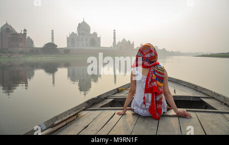 Eine junge Frau beobachten Sonnenuntergang über Taj Mahal von einer hölzernen Boot. Stockfoto