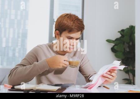 Unglückliche Menschen Rechnungen bezahlen auf seinem Laptop im Wohnzimmer Stockfoto