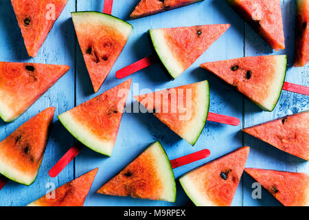 Sommer Konzept Wassermelone Schicht Eis am Stiel auf einem blauen rustikal Holz Hintergrund Stockfoto