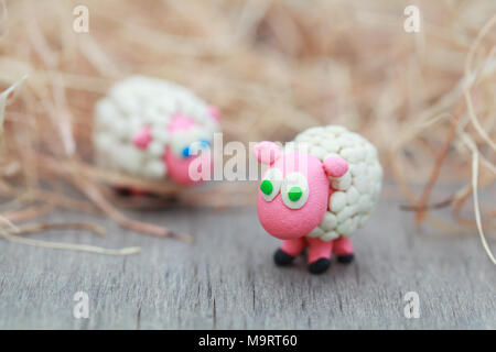 Plastilin Welt - kleine Hausgemachte weiße Schafe stehen auf einer Farm auf dem Hintergrund von Heu, selektiver Fokus auf den ersten Stockfoto