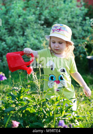 Kleines Mädchen Blumen gießen im Garten niedlich, selektiven Fokus Stockfoto