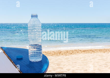 Flasche Wasser am Strand Tabelle unter freiem Himmel auf dem Hintergrund von Meer. Stockfoto