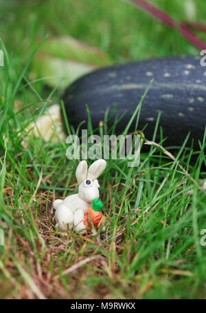 Plastilin Welt - Kleine hausgemachte Weisser Hase mit Möhre sitzen in der Nähe von Zucchini, selektiven Fokus Stockfoto