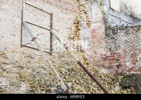 Alte Ruinen alter Mauer. Verwitterte Fassade von rostigem Eisen Bau unterstützt. Stockfoto